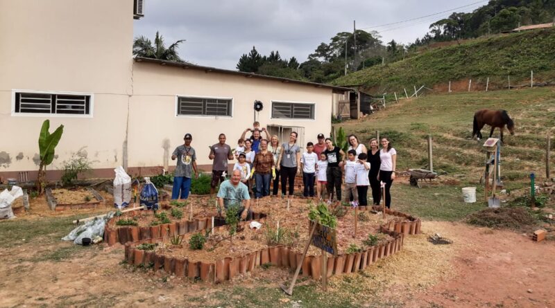 Membros da comunidade e da equipe do CRAS Silvio Schramm na horta comunitária do local.